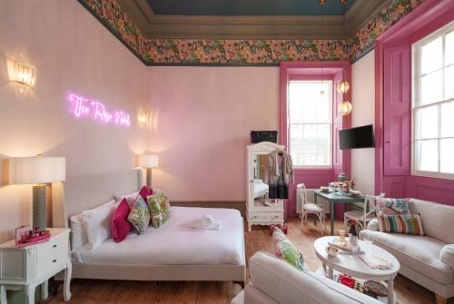 The Rose Nobel - 1 Bed Studio Apartment in Bristol by Mint Stays في بريستول: غرفة معيشة بجدران وردية وأريكة بيضاء