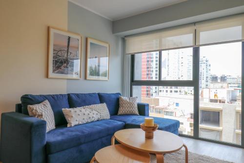 a blue couch in a living room with a large window at El Sol by Wynwood House in Lima