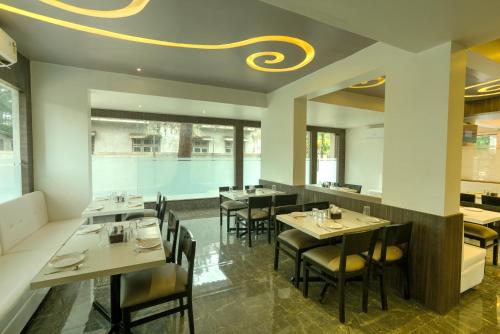 un ristorante con tavoli, sedie e soffitto di Crown Inn a Panvel