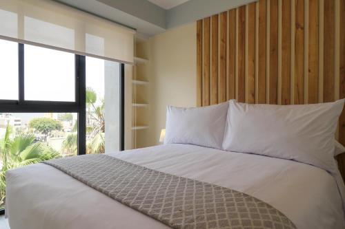 a bedroom with a white bed with a large window at El Sol by Wynwood House in Lima