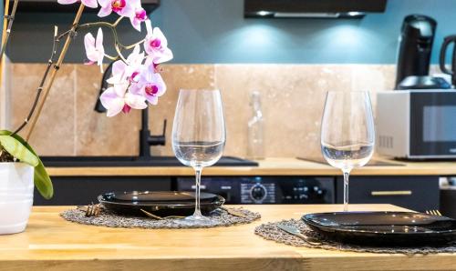 two wine glasses sitting on top of a wooden table at Le Cinq Bis : centre-ville*proche gare*parking in Vesoul