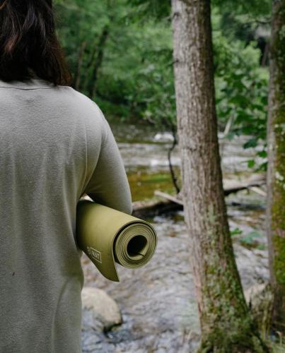 a person is holding a cup in the woods at Auberge Yoga Salamandre in Lac-Brome