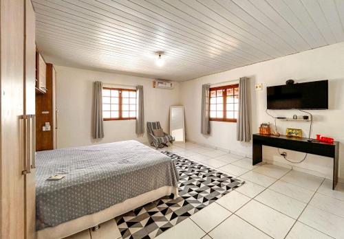 a bedroom with a bed and a desk and a television at Otima casa com praia particular em Camacari BA in Camaçari
