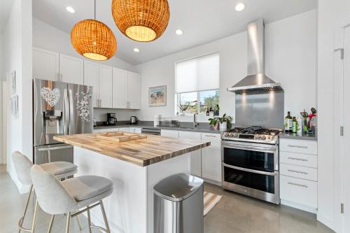 a kitchen with white cabinets and a wooden counter top at Whistling Cloud/ Design+Desert Views+National Park in Joshua Tree