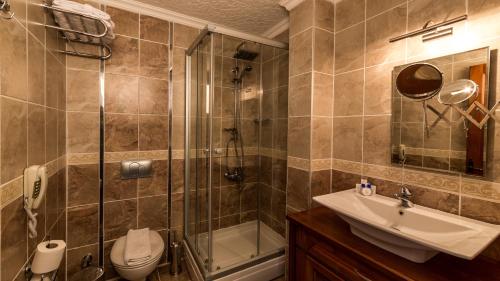 a bathroom with a shower and a toilet and a sink at Palmetto Resort Hotel Selimiye in Selimiye