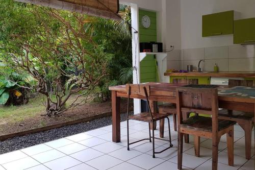 eine Küche mit einem Holztisch und Stühlen in der Unterkunft PAPAYE VERTE habitation CALISSA in Bouillante