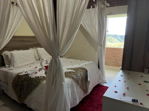 a bedroom with a bed with white curtains and a window at Pedra do Sino Hotel in Piranhas