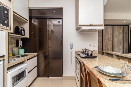 una cucina con mobili bianchi e un piano di lavoro di Studio moderno em condomínio de luxo pé na areia a Santos
