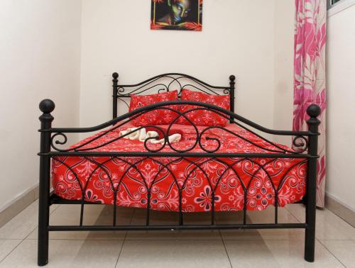 una cama negra con almohadas rojas en una habitación en Résidence Céline, en Libreville