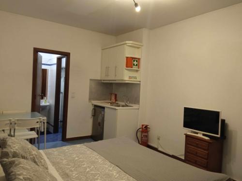 a bedroom with a bed and a tv and a kitchen at My Colombo Place in Lisbon