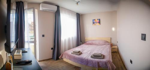 a small bedroom with a bed with a purple blanket at GRAND APARTMENT OHRID - top center near to sea and sea garden in Burgas City