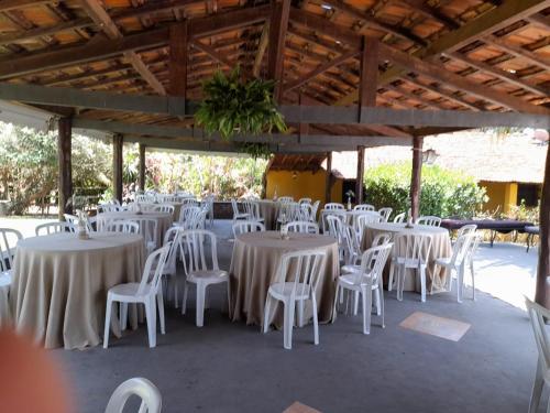 een groep tafels en witte stoelen in een paviljoen bij Estância São Sebastião in Cafelândia