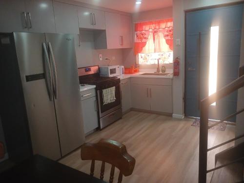 a kitchen with white cabinets and a refrigerator at COZY POD in Dabadie
