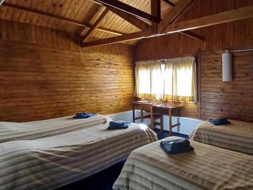 a bedroom with two beds and a desk in it at ESTANCIA LA SERENA in Perito Moreno