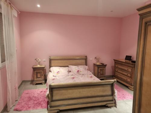 - une chambre avec un lit aux murs roses et une commode dans l'établissement Maison moderne et lumineuse, à Castillonnès