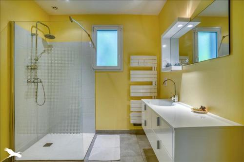 La salle de bains jaune est pourvue d'une douche et d'un lavabo. dans l'établissement Maison moderne et lumineuse, à Castillonnès