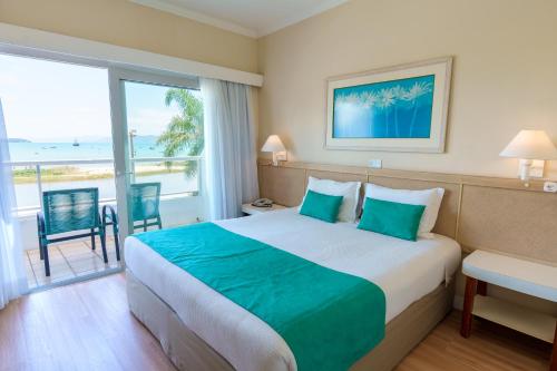 a hotel room with a bed and a view of the ocean at Costa Norte Ponta das Canas Hotel in Florianópolis