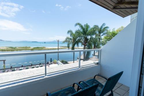 a balcony with two chairs and a view of the beach at Costa Norte Ponta das Canas Hotel in Florianópolis