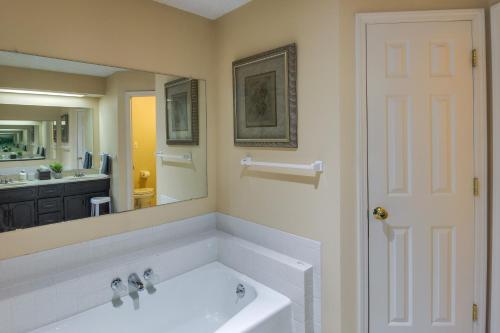 baño con bañera blanca y espejo grande en Overland Park Family Home with Game Room and Backyard!, en Overland Park