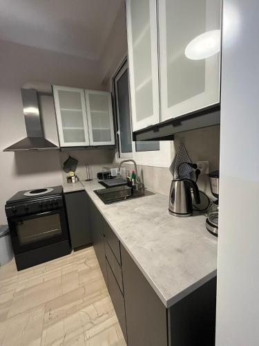 a kitchen with white cabinets and a black stove at Katerina Holiday House in Anavissos