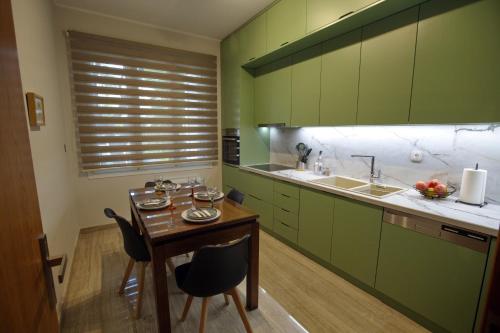 a kitchen with green cabinets and a table and chairs at AKAKIA VILLA NAFPLIO in Nafplio