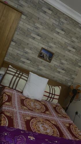 1 dormitorio con cama con almohadas y pared de ladrillo en Yessit Homestay en Abuja