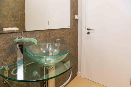 un lavandino in vetro su un tavolo in vetro in bagno di Mosteiros Beach House a Mosteiros