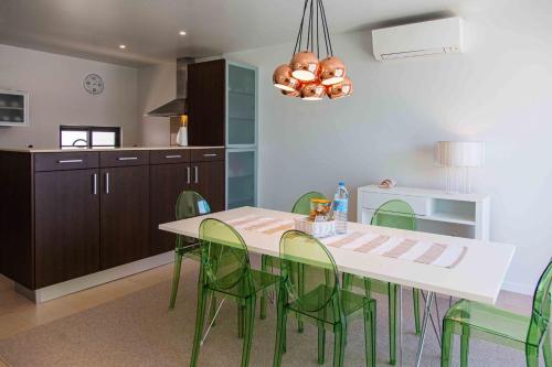 a dining room with a table and green chairs at Mosteiros Beach House in Ponta Delgada