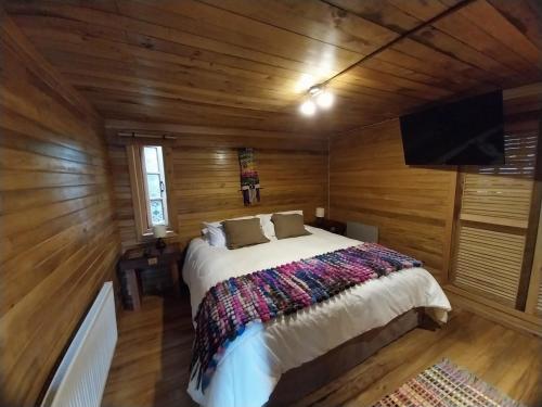 a bedroom with a bed in a room with wooden walls at ALMA CHILOTA in Castro