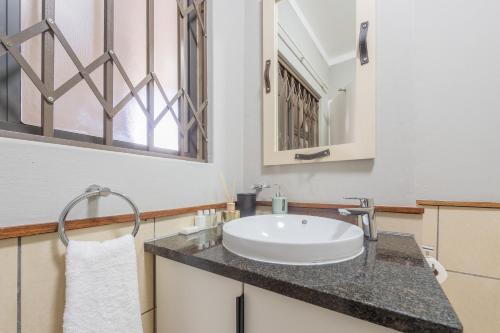 ein Bad mit einem Waschbecken und einem Spiegel in der Unterkunft The Paddocks - Luxury Studio with Backup Power in Sandton