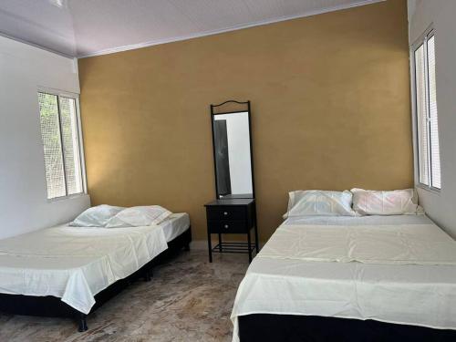 two beds in a room with two windows at Finca Nirvana. in Agua de Dios