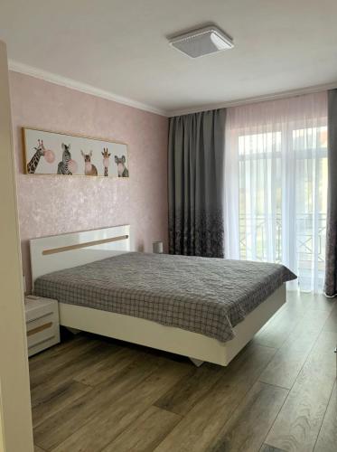 a bedroom with a bed and a large window at Mint Apartment Солнечное Закарпатье in Polyana