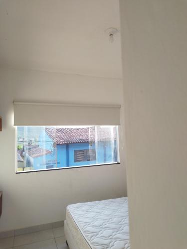 um quarto branco com uma cama e uma janela em Hostel em Capitólio