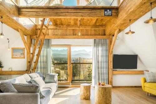 un soggiorno con soffitti in legno e una grande finestra di Rent like home - Willa Zoniówka PREMIUM a Zakopane