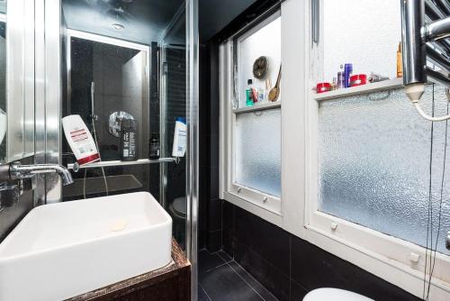 La salle de bains est pourvue d'un lavabo et d'une fenêtre en verre. dans l'établissement Chic Flat in Oxford Circus, à Londres