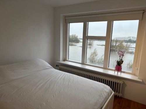 a bedroom with a bed and a window with flowers at Mooie kamer uitzicht op de ijssel/ Nice room with beautiful view of the Ijssel river in Wijhe