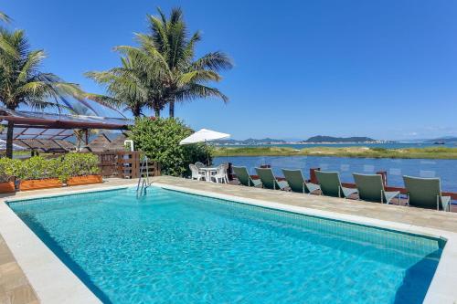 a swimming pool with chairs and a view of the water at Costa Norte Ponta das Canas Hotel in Florianópolis