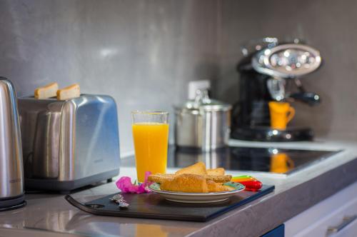 a plate of food and a glass of orange juice at Lindos Allure Villa with Jacuzzi and Acropolis view!!! in Líndos