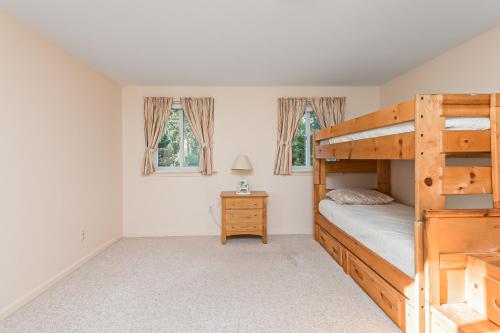 a bedroom with a bunk bed and two windows at Mill Pond Vista in Chatham