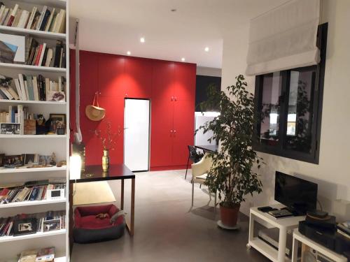 - un salon avec un mur rouge, une table et un bureau dans l'établissement Appartement charmant à Saint-Ouen avec terrasse & vue sur ville, à Saint-Ouen