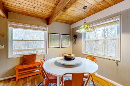 a dining room with a table and chairs and two windows at Bryson Chalet in Bryson City