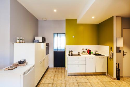 een keuken met witte kasten en een gele muur bij Appartement d'une chambre avec vue sur la ville terrasse et wifi a Charleville Mezieres a 4 km de la plage in Charleville-Mézières