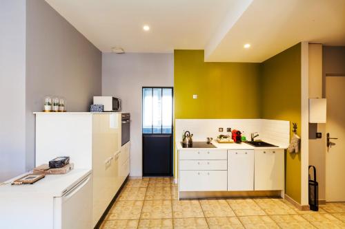 une cuisine avec des placards blancs et un mur jaune dans l'établissement Appartement charmant Charleville-Mézières 45m² Vue sur la ville, à Charleville-Mézières