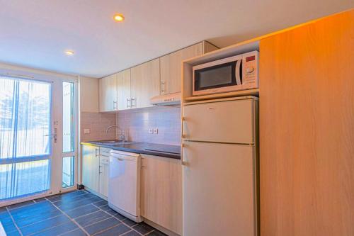 La cuisine est équipée d'un réfrigérateur blanc et d'un four micro-ondes. dans l'établissement Charmante maison à Guidel, piscine partagée, vue mer, à Guidel