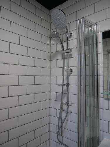a shower in a bathroom with white tiles at Queens Cottage, Wivenhoe Stylish, Plush, Cosy, Convenient & Quirky, 2x Double Bed Period Cottage PLUS Patio - 9 min walk train, 4 min walk High Street Pubs, Restaurants, Shops in Wivenhoe