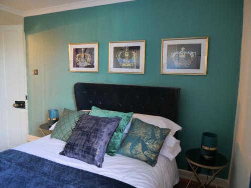 een slaapkamer met een bed met een blauwe muur bij Queens Cottage, Wivenhoe Stylish, Plush, Cosy, Convenient & Quirky, 2x Double Bed Period Cottage PLUS Patio - 9 min walk train, 4 min walk High Street Pubs, Restaurants, Shops in Wivenhoe