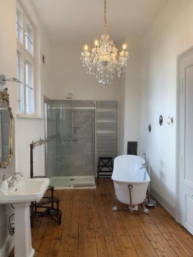 a bathroom with a chandelier and a tub and sink at Napoleonsuite auf Schloß Hürbel in Gutenzell-Hürbel