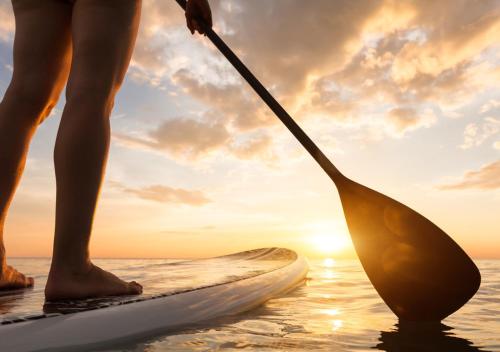 a person standing on a paddle board in the water at Zima Two Seaside in Zygi