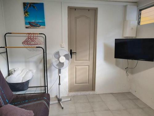 un soggiorno con ventilatore e porta di Studio avec terrasse et wifi a Le Marin a 5 km de la plage a Le Marin