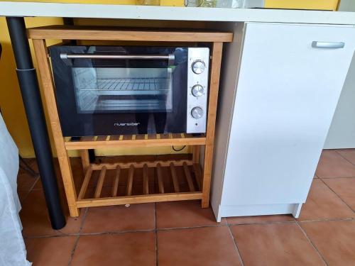 un forno a microonde seduto in un supporto con forno a microonde di Studio avec terrasse et wifi a Le Marin a 5 km de la plage a Le Marin